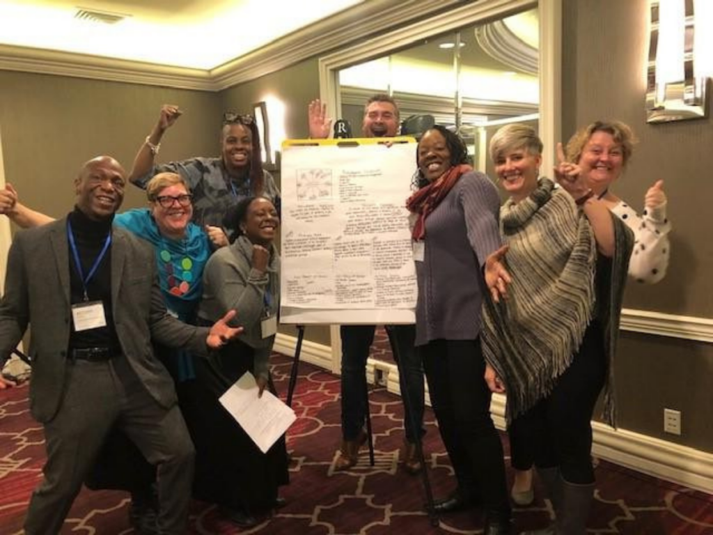 A group of CSH team members smiling around a flipchart