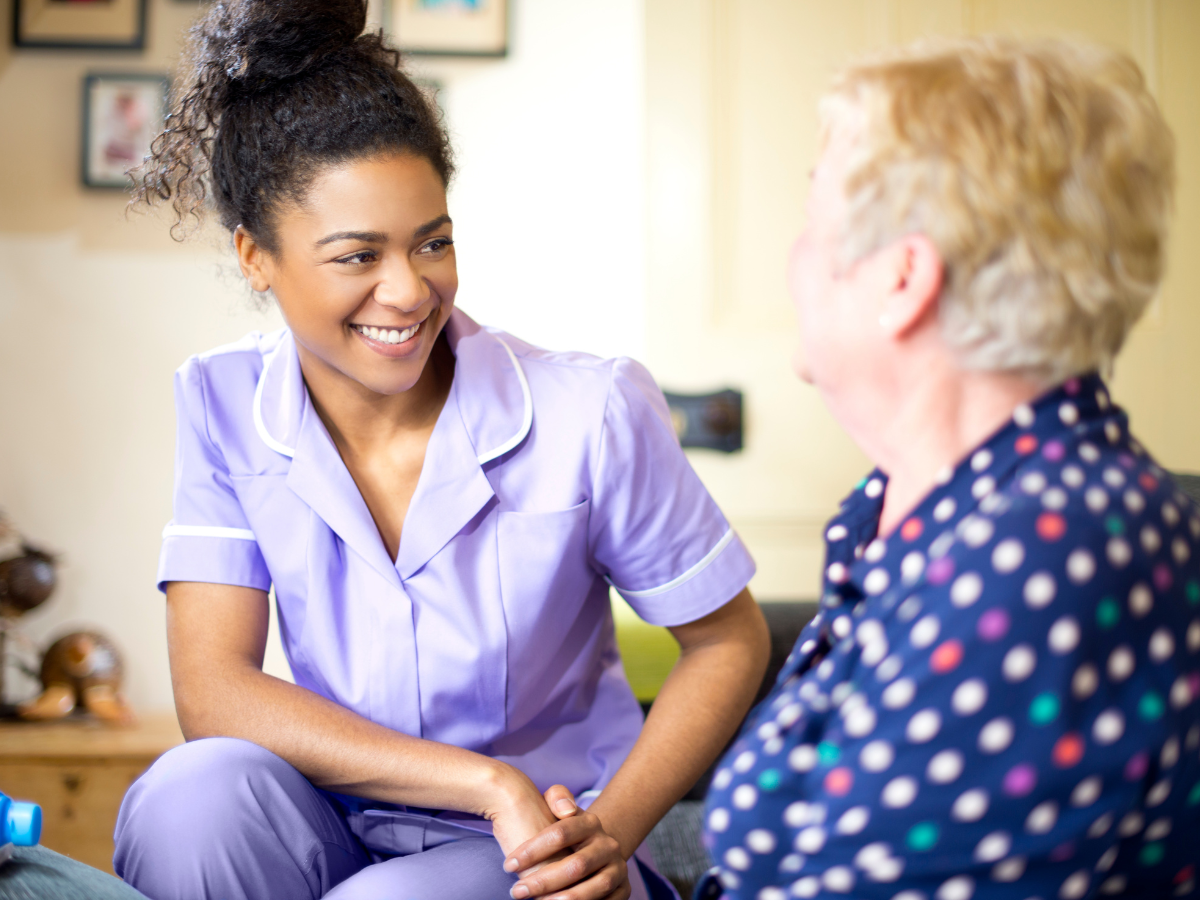 care worker looking at white aging woman patient in home setting