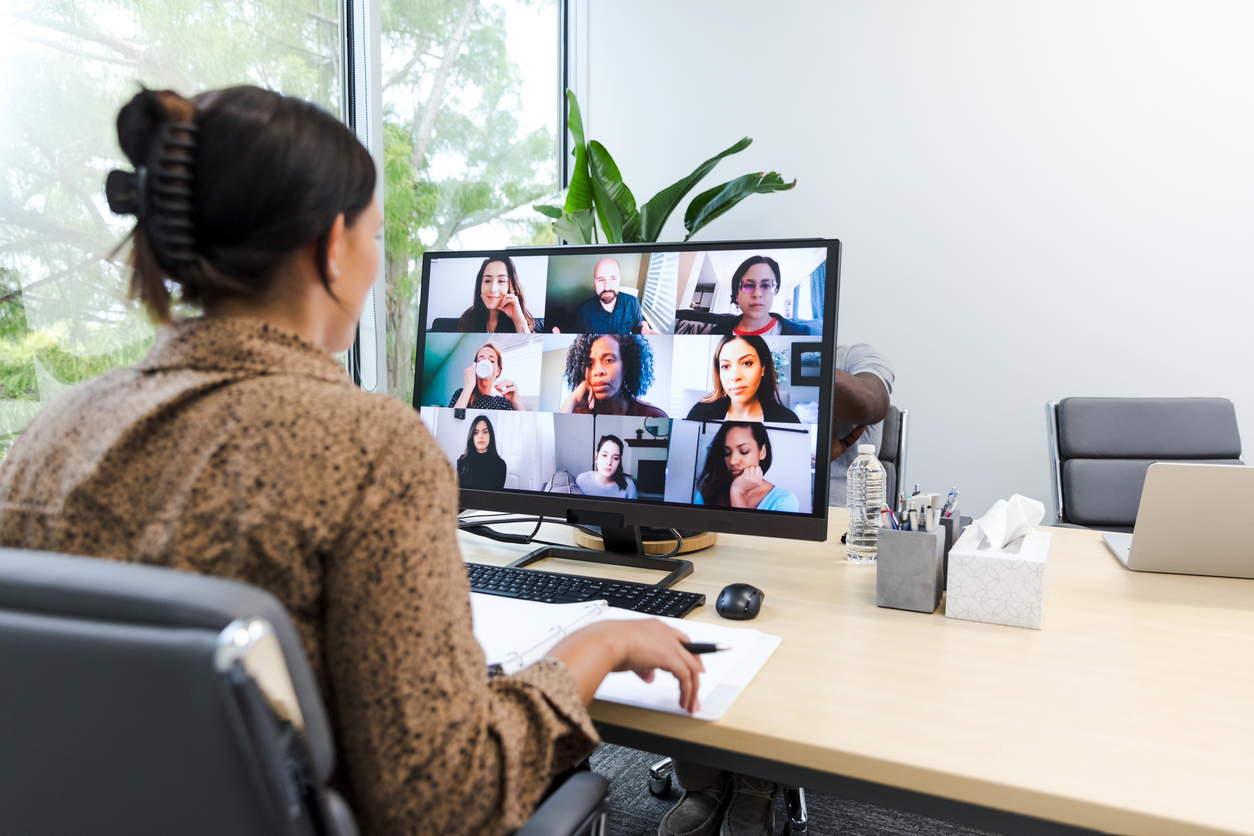 Photo of a woman sitting at a desk participating in a virtual meeting as seen on her laptop.