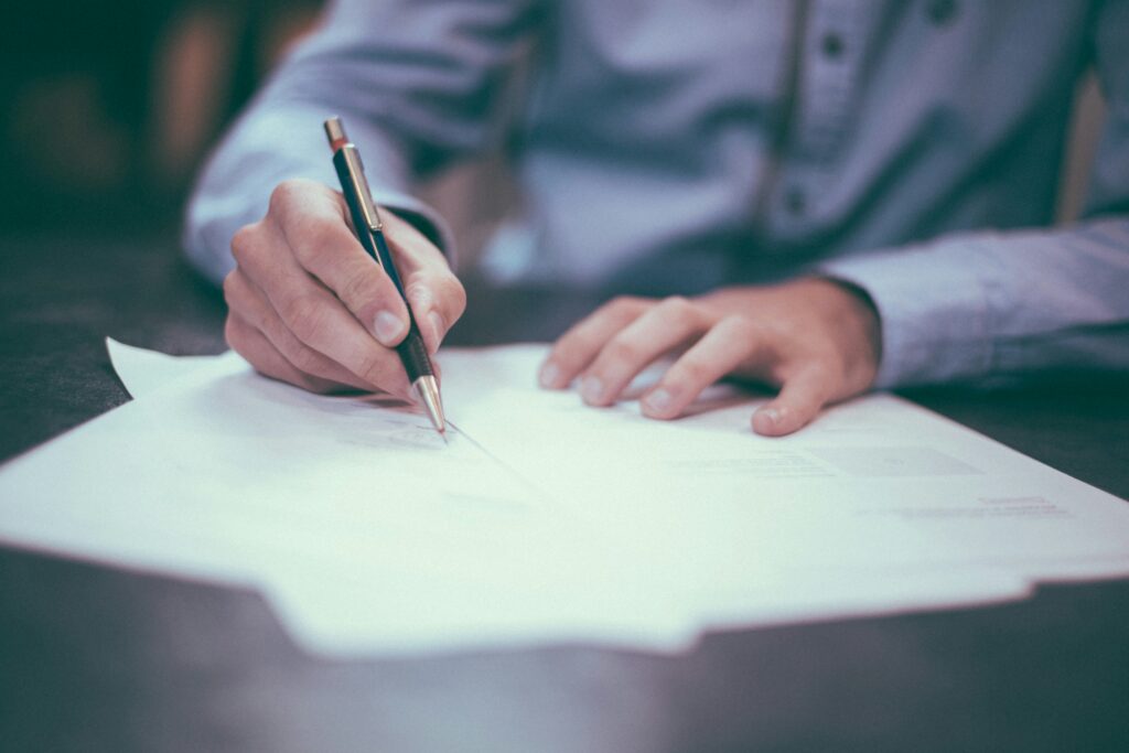 person holding a pen writing on paper